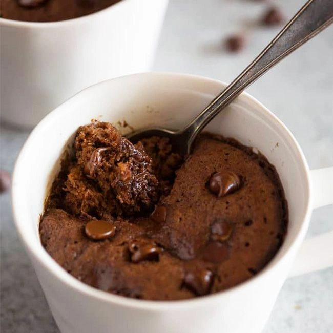Bolo de caneca fit de chocolate com gotas derretidas, servido na caneca branca